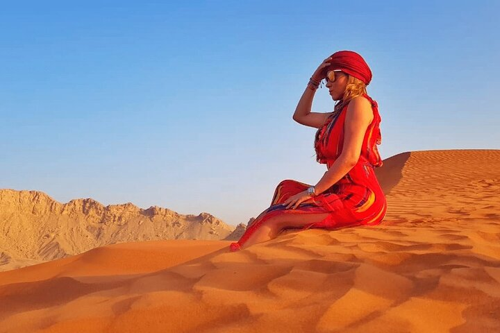 Experience the serene beauty of Dubai's red dunes where golden sands meet endless skies inviting you to explore the rich traditions of Bedouin culture in a stunning desert landscape.
